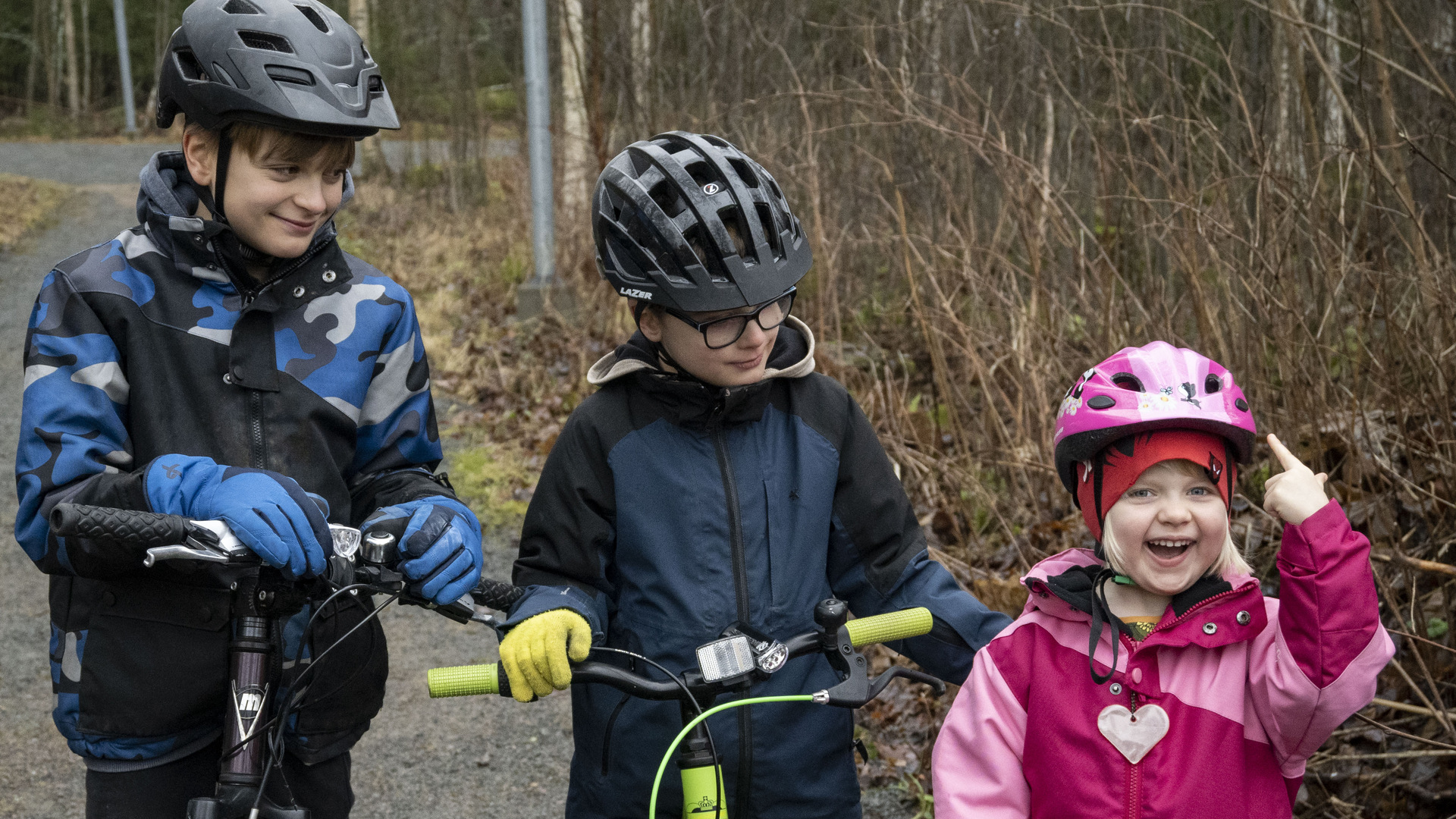 Tre barn med cyklar och hjälmar.