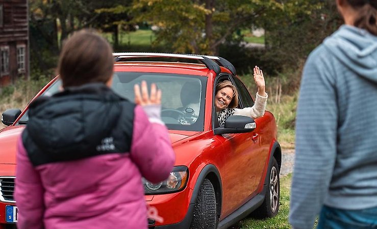 en person som vinkar från en bil